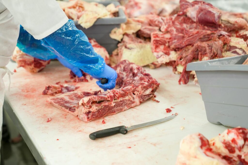Butcher slicing raw meat on a table in NC. Focus on freshness and precision.